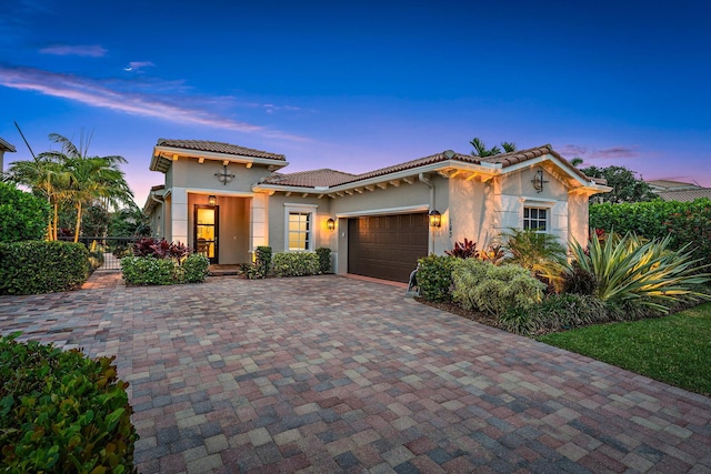 view of front of house with stucco siding, decorative driveway, an attached garage, and a tile roof