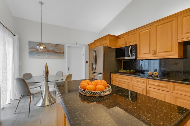 kitchen featuring stainless steel appliances, dark stone countertops, and backsplash