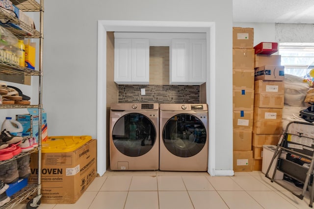 laundry room featuring washer and dryer, cabinet space, and light tile patterned floors