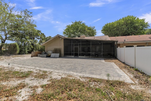 back of property with fence, stucco siding, a sunroom, and a patio