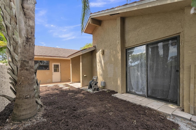 back of house featuring a tile roof and stucco siding