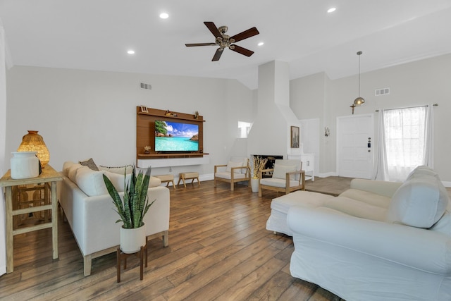 living room featuring wood finished floors, vaulted ceiling, visible vents, and recessed lighting