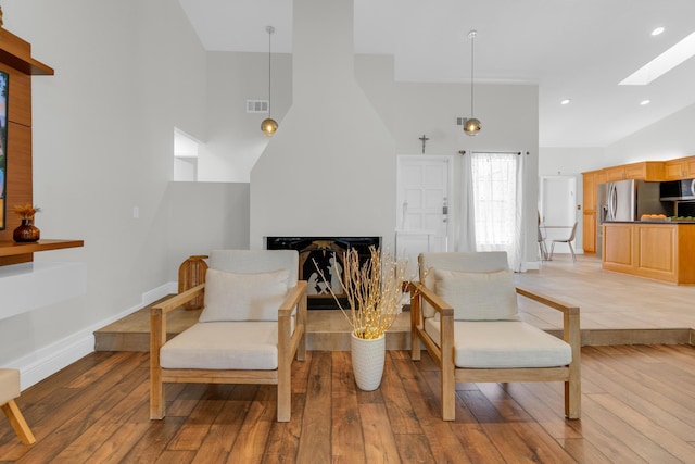 living area featuring a fireplace, light wood-style floors, visible vents, and a skylight