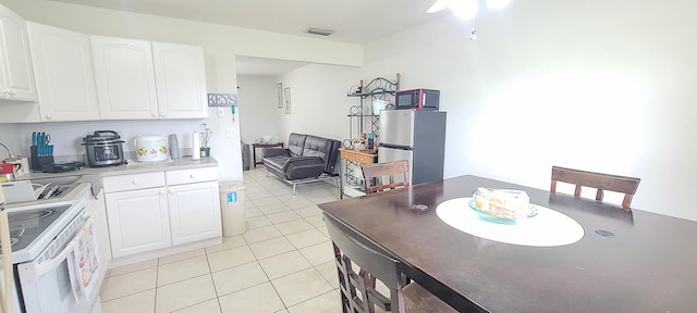 kitchen featuring freestanding refrigerator, light tile patterned floors, white range with electric cooktop, white cabinetry, and visible vents