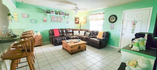 living room with baseboards, a textured ceiling, a ceiling fan, and light tile patterned flooring