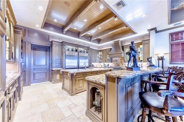 3131 NE 27th Ave, Lighthouse Point, FL 33064 - kitchen featuring wood ceiling with exposed beams, a kitchen bar, a sink, stainless steel built in fridge, and an island with sink