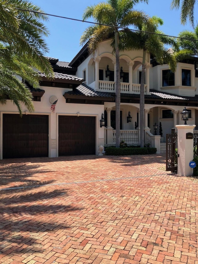 3131 NE 27th Ave, Lighthouse Point, FL 33064 - view of front facade featuring covered porch, a balcony, stucco siding, a garage, and decorative driveway