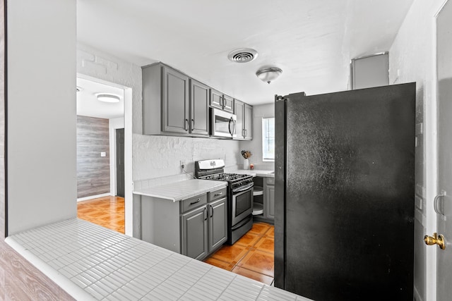 3700 N Australian Ave, West Palm Beach, FL 33407 - kitchen with stainless steel appliances, gray cabinetry, light countertops, and light tile patterned floors