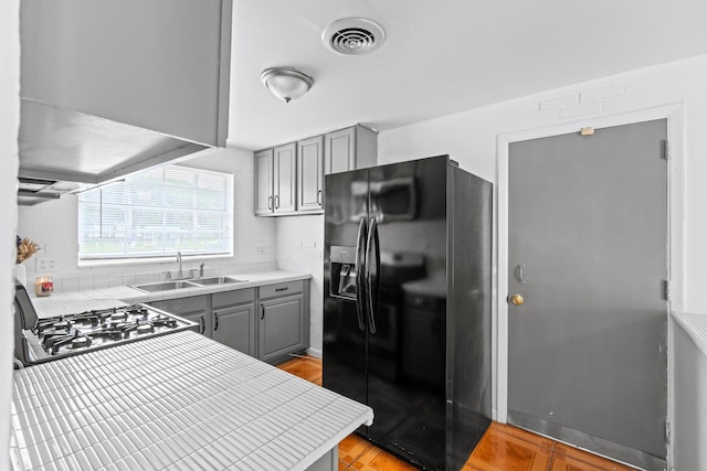 3700 N Australian Ave, West Palm Beach, FL 33407 - kitchen with black refrigerator with ice dispenser, gray cabinetry, a sink, range, and tile countertops
