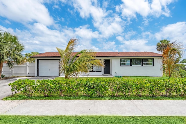 3700 N Australian Ave, West Palm Beach, FL 33407 - ranch-style house with stucco siding, an attached garage, fence, and driveway