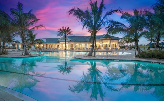 pool at dusk featuring a community pool and a patio