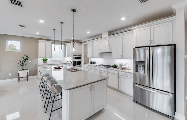 kitchen featuring stainless steel appliances, a sink, white cabinetry, light tile patterned floors, and a kitchen bar