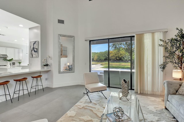 living room featuring concrete floors, a towering ceiling, visible vents, and baseboards