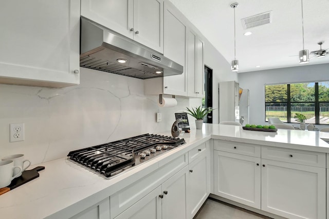 kitchen with stainless steel gas cooktop, under cabinet range hood, decorative backsplash, and visible vents