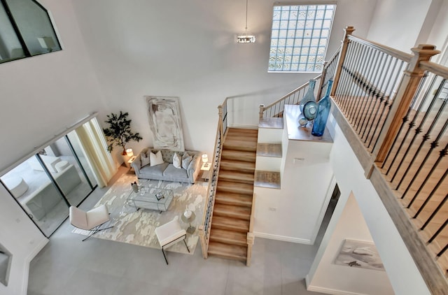 stairs featuring a high ceiling, baseboards, and tile patterned flooring