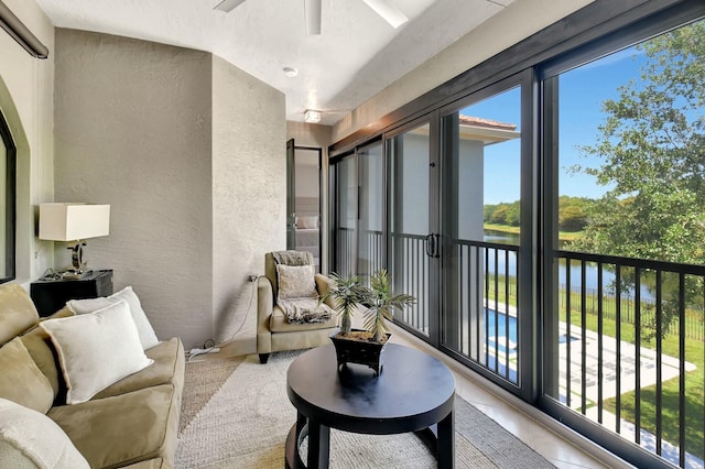 interior space featuring a textured wall, plenty of natural light, a water view, and a ceiling fan