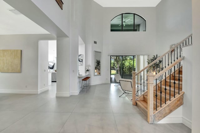 tiled entryway featuring stairs, visible vents, baseboards, and a ceiling fan