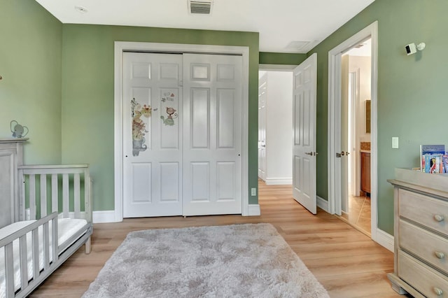 bedroom with light wood-style floors, a closet, baseboards, and visible vents