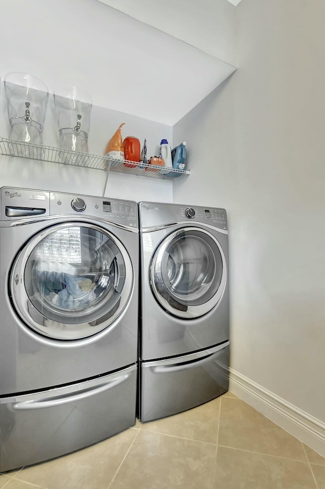 washroom with washer and dryer, laundry area, baseboards, and tile patterned floors