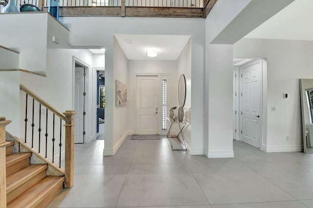 foyer entrance with stairs, light tile patterned floors, and baseboards