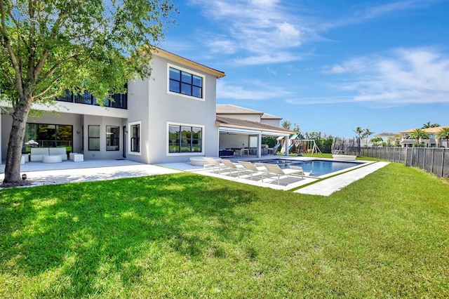 back of house featuring a fenced backyard, stucco siding, a lawn, a patio area, and a playground