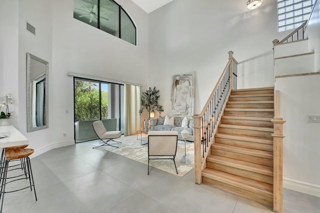 stairway featuring visible vents, baseboards, and a high ceiling