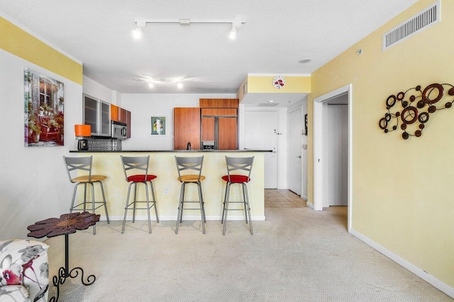 1551 N Flagler Dr Unit 1509, West Palm Beach, FL 33401 - kitchen featuring visible vents, a kitchen breakfast bar, a peninsula, stainless steel microwave, and light colored carpet