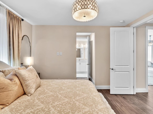 bedroom featuring baseboards, dark wood-style floors, and connected bathroom