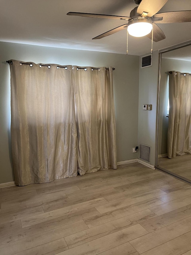 unfurnished room featuring light wood-type flooring, ceiling fan, baseboards, and visible vents