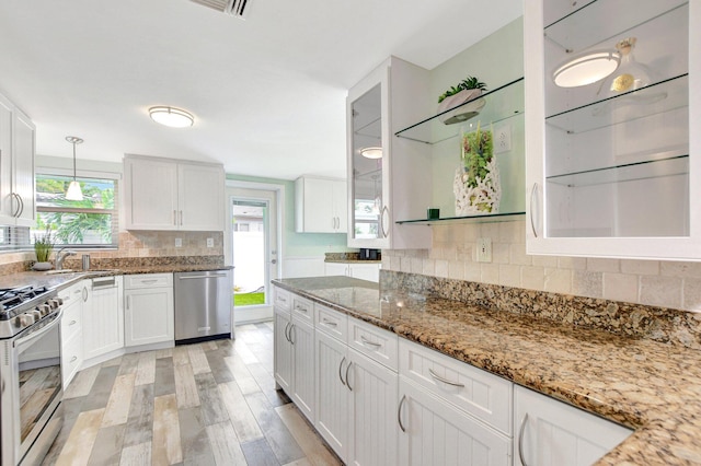kitchen with white cabinets, appliances with stainless steel finishes, a sink, and light stone countertops
