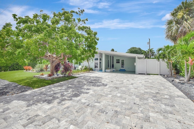 view of front facade featuring a front lawn, an attached carport, a gate, and decorative driveway