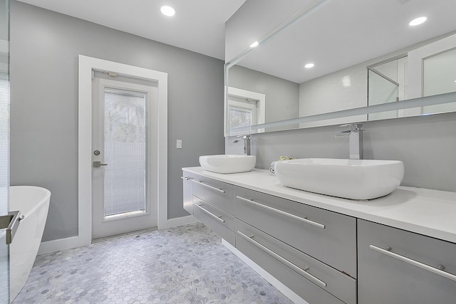 1900 NE 16th Ter, Fort Lauderdale, FL 33305 - bathroom with a freestanding tub, double vanity, a sink, and baseboards