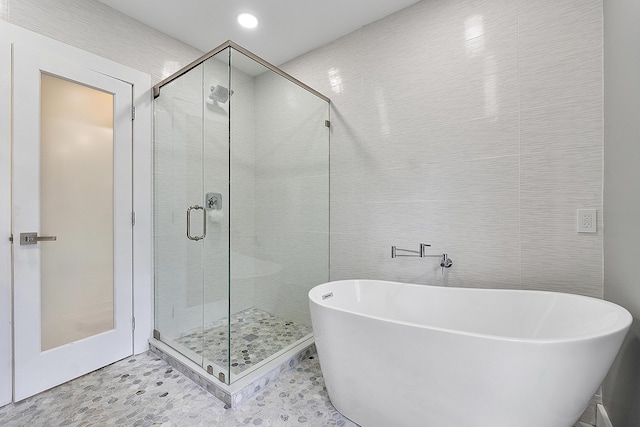 1900 NE 16th Ter, Fort Lauderdale, FL 33305 - full bathroom featuring a shower stall, a freestanding tub, and tile walls