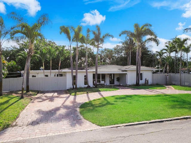 1900 NE 16th Ter, Fort Lauderdale, FL 33305 - view of front facade with curved driveway, a fenced front yard, stucco siding, a front lawn, and a gate