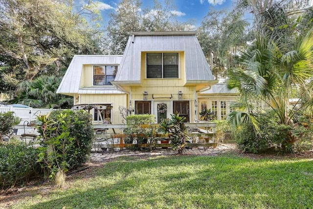 rear view of house with a lawn, fence, and metal roof