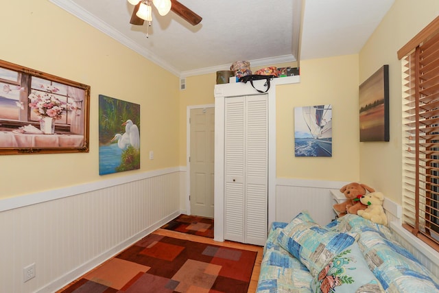bedroom featuring a closet, wainscoting, crown molding, and wood finished floors