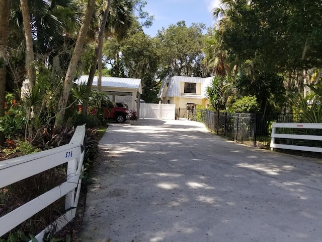 view of car parking featuring fence, a detached carport, and driveway