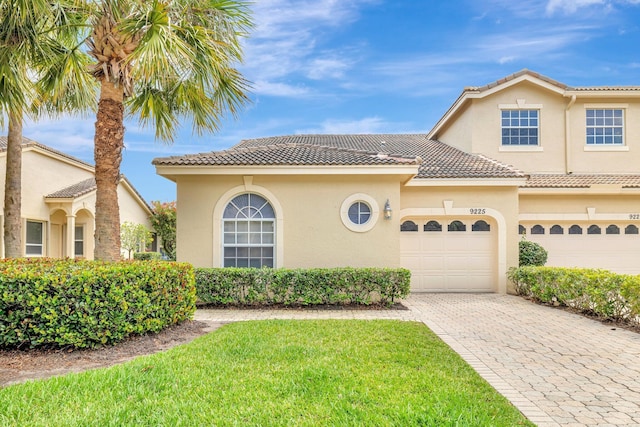 9225 Wentworth Ln, Port Saint Lucie, FL 34986 - mediterranean / spanish-style house with an attached garage, a tiled roof, stucco siding, and decorative driveway