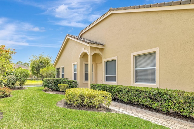 9225 Wentworth Ln, Port Saint Lucie, FL 34986 - view of side of property with a yard, stucco siding, and a tiled roof