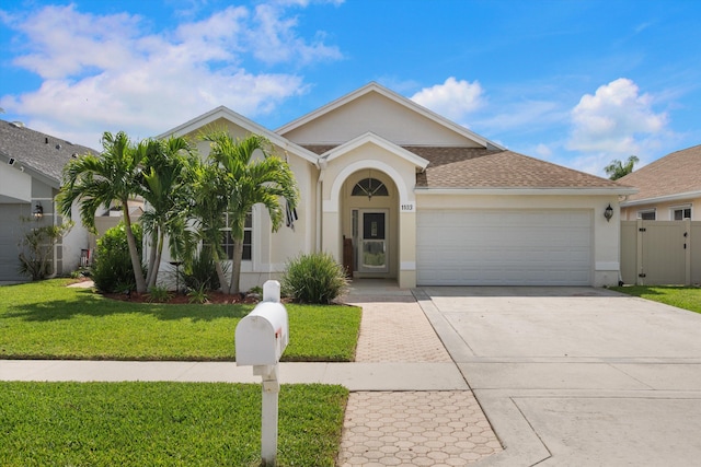 1103 Aviary Rd, Wellington, FL 33414 - view of front of home with a shingled roof, an attached garage, stucco siding, a front lawn, and driveway