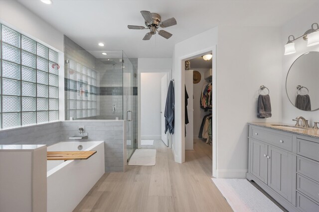 1103 Aviary Rd, Wellington, FL 33414 - bathroom featuring vanity, a ceiling fan, a shower stall, a garden tub, and wood finished floors