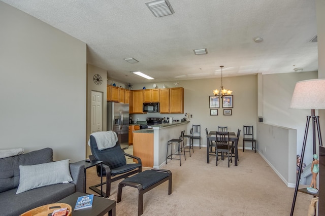 living area featuring an inviting chandelier, a textured ceiling, light colored carpet, visible vents, and baseboards