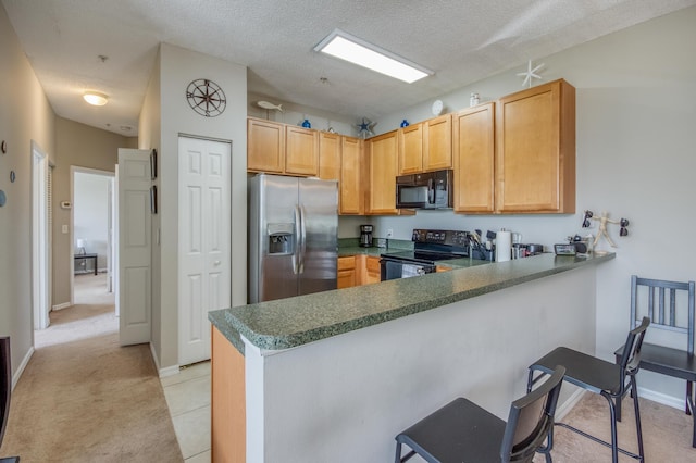 kitchen with black appliances, a kitchen breakfast bar, a peninsula, and a textured ceiling