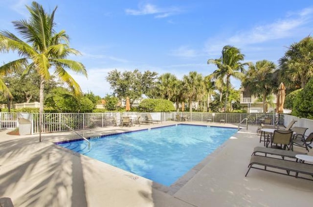 pool with a patio area and fence