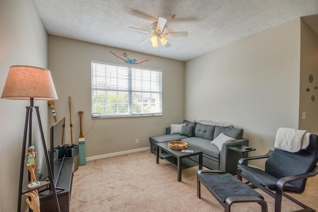 living room with baseboards, a ceiling fan, light carpet, and a textured ceiling