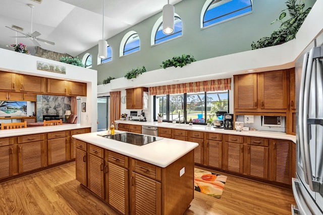 3120 SE Downwinds Rd, Jupiter, FL 33478 - kitchen with a high ceiling, a fireplace, ceiling fan, light countertops, and appliances with stainless steel finishes
