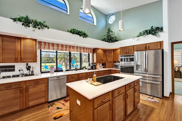 3120 SE Downwinds Rd, Jupiter, FL 33478 - kitchen with a towering ceiling, light wood finished floors, a sink, and stainless steel appliances