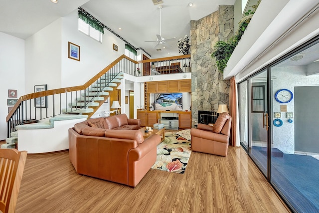 3120 SE Downwinds Rd, Jupiter, FL 33478 - living room featuring a towering ceiling, ceiling fan, stairway, and light wood-style floors