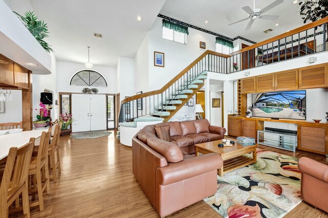 3120 SE Downwinds Rd, Jupiter, FL 33478 - living area featuring stairway, ceiling fan, light wood-style floors, and a high ceiling