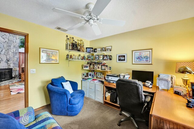 3120 SE Downwinds Rd, Jupiter, FL 33478 - office area with ceiling fan, a stone fireplace, visible vents, carpet, and a textured ceiling